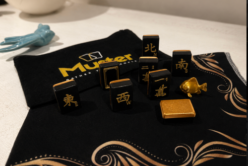 Dynasty Noir mahjong tiles in black and gold with Muster branding